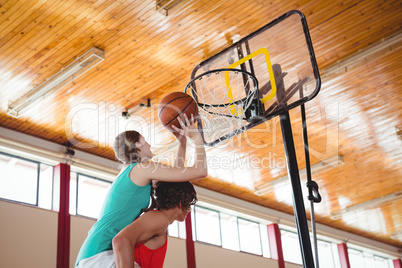 Man assisting female friend while playing basketball