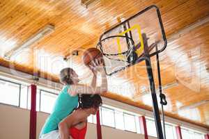Man assisting female friend while playing basketball