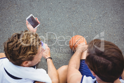 Overhead view of basketball player showing mobile phone to friend