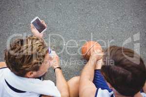 Overhead view of basketball player showing mobile phone to friend