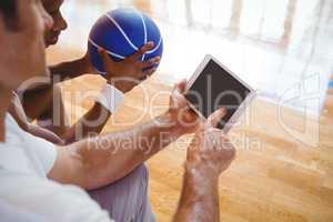 High angle view of coach showing digital tablet to basketball player