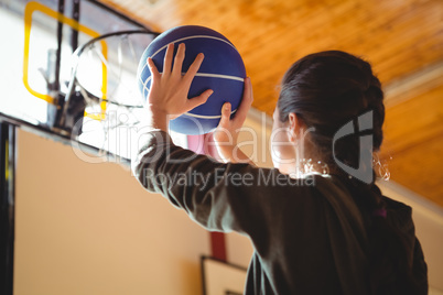 Side view of young woman practicing basketball in court