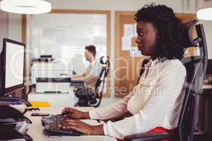 Side view of businesswoman working on computer at desk