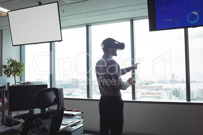 Businessman using virtual reality glasses against glass windows