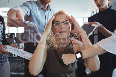 Frustrated businesswoman amidst team holding technologies