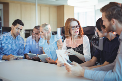 Business people discussing while holding digital tablets