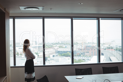 Side view of businesswoman looking out through glass window at office