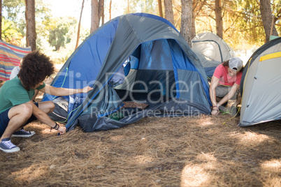 Male friends making tent on field