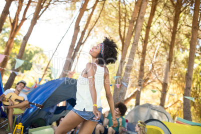 Happy young woman standing with friends sitting in background