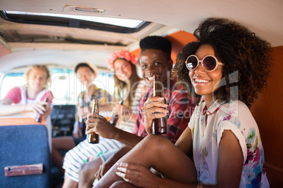 Portrait of smiling friends holding beer bottles in camper van