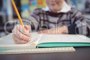 Mid section of schoolboy studying while sitting at desk