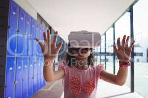 Schoolgirl anticipating while using virtual reality glasses in corridor