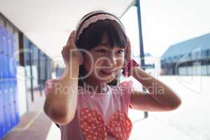 Smiling girl listening music through headphones in corridor