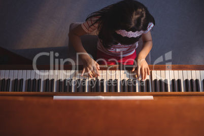 Overhead view of elementary girl playing piano in classroom