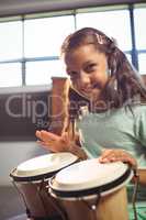 Portrait of smiling girl playing bongo drums