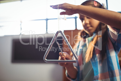 Girl playing triangle in classroom
