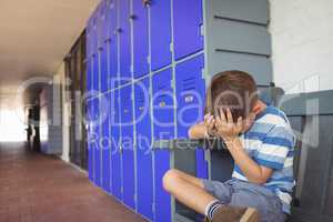 Unhappy boy sitting on bench in corridor