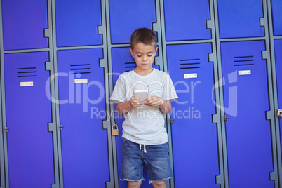 Boy using mobile phone against lockers