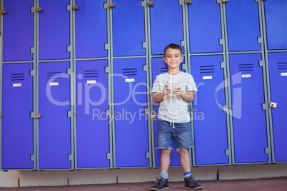 Portrait of smiling boy using mobile phone against lockers