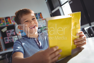 Happy boy reading book in classroom
