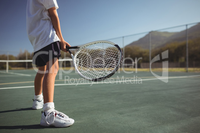 Girl holding tennis racket while standing on court