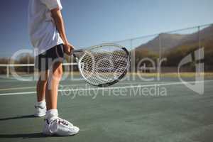 Girl holding tennis racket while standing on court