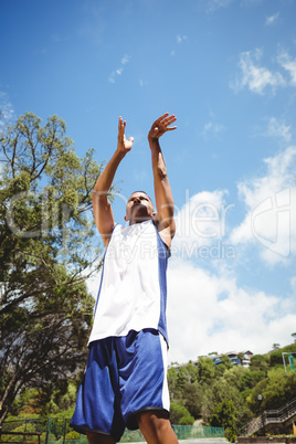 Low angle view of male teenager practicing basketball