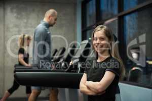 Smiling woman standing with people exercising on treadmill