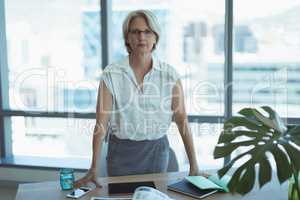 Portrait of businesswoman standing by desk
