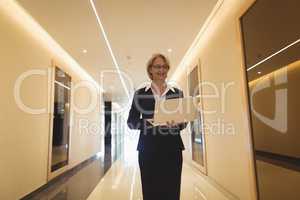 Smiling businesswoman using laptop in corridor