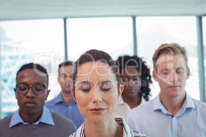 Close up of business colleagues with eyes closed at office