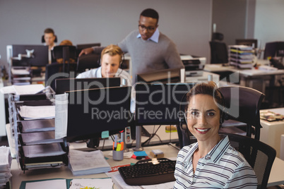 Smiling businesswoman sitting on chair with colleagues working at office