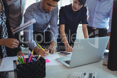 Businessman drawing on paper while working with team