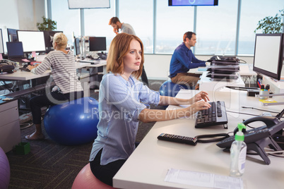 Thoughtful businesswoman sitting on exercise ball at office