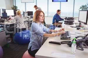 Thoughtful businesswoman sitting on exercise ball at office