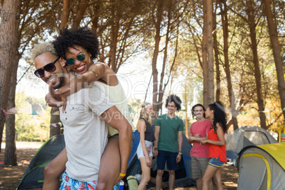 Man piggybacking woman with friends in background