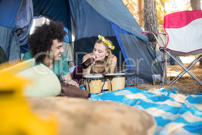 Woman having drink while relaxing with boyfriend in tent