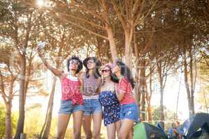 Happy female friends taking selfie at campsite