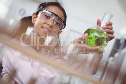 Portrait of elementary student holding green chemical in beaker at laboratory