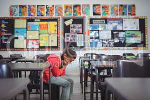 Side view of girl sitting on chair in classroom