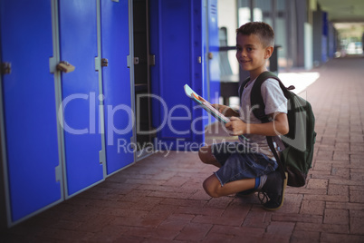 Portrait of boy holding books by open locker