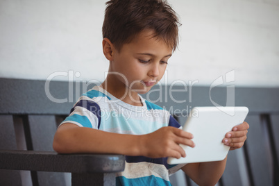 Boy using digital tablet while sitting on bench