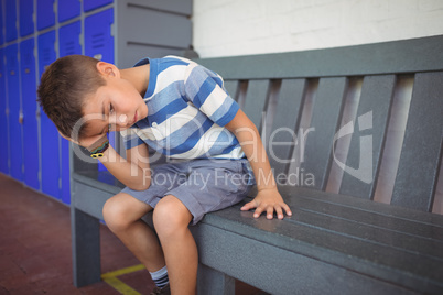 Thoughtful elementary boy sitting on bench