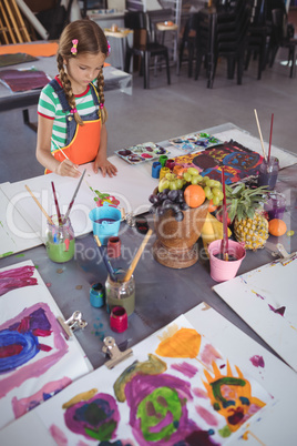High angle view of elementary girl painting on paper