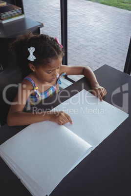 Girl reading braille at desk in library