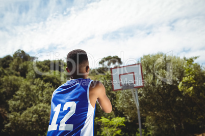 Rear view of teenage boy practicing basketball