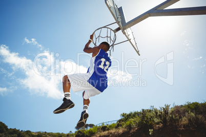Rear view of man hanging on basketball hoop