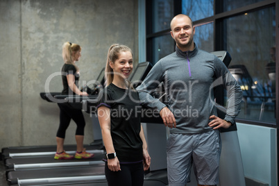 Portrait of friends standing with woman exercising on treadmill