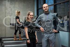 Portrait of friends standing with woman exercising on treadmill