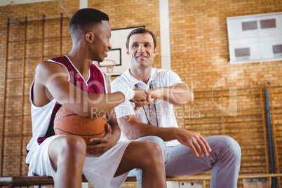 Basketball player doing fist bump with coach